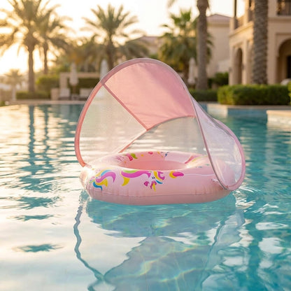 A pink inflatable pool float with a matching pop-up sun canopy floating on a swimming pool, with palm trees and a resort-style building blurred in the background.